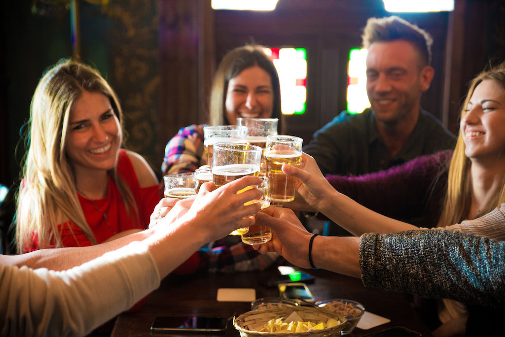 Group of apartment friends toasting with drinks at Denver bar